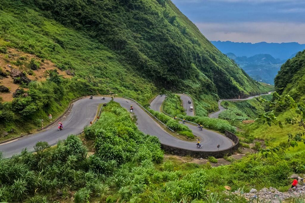 The zigzag road with motorbikes of the Tham Ma Pass along the Ha Giang Loop